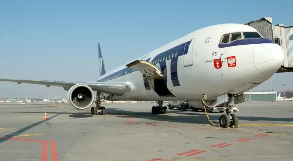 Samolot LOT-u na płycie lotniska, gotowy do startu. Zastanawiasz się, jak zbierać mile lotnicze? Podróżuj tymi liniami!