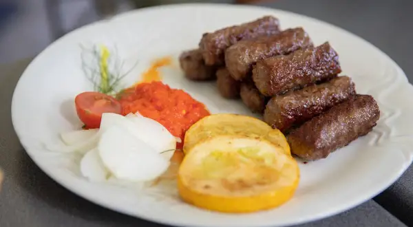 Cevapi, klasyka kuchni słoweńskiej, podane z ajwarem, cebulą i pomidorem.