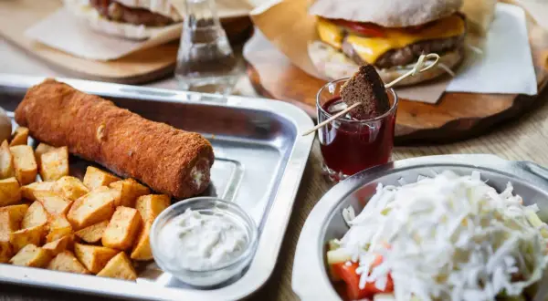 Sycące dania kuchni serbskiej: panierowany rolka mięsa z frytkami, burger i sałatka.