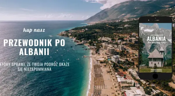 Piękna linia brzegowa Albanii, z widokiem na miasto i góry. Na ekranie telefonu przewodnik po Albanii, idealny na podróż.