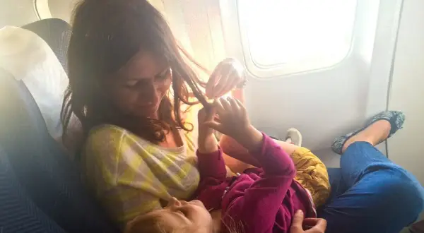 Mama bawi się włosami dziecka w samolocie. Dzieci w samolocie, podróżują z uśmiechem.