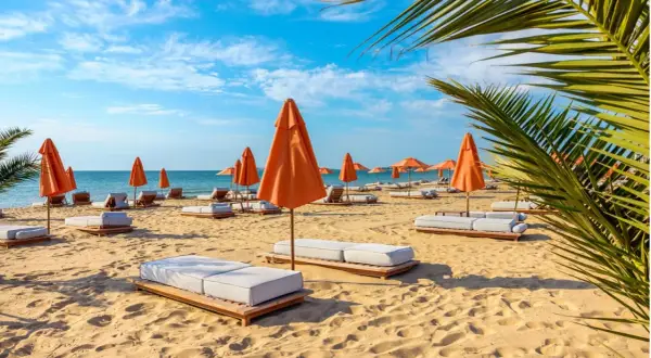 Słoneczny dzień na plaży w Złotych Piaskach. Pomarańczowe parasole i leżaki czekają na gości.