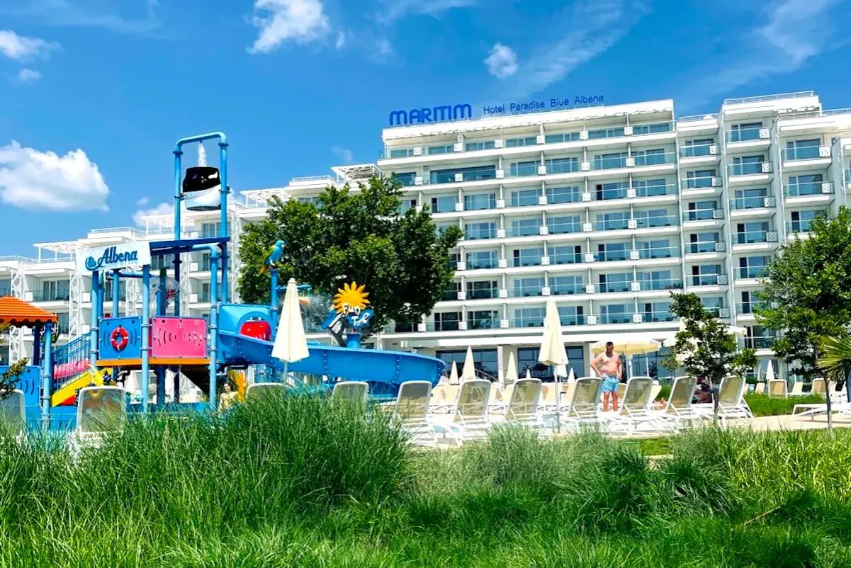 Kolorowy aquapark i hotel Maritim Paradise Blue Albena w Bułgarii, z leżakami i zieloną trawą.