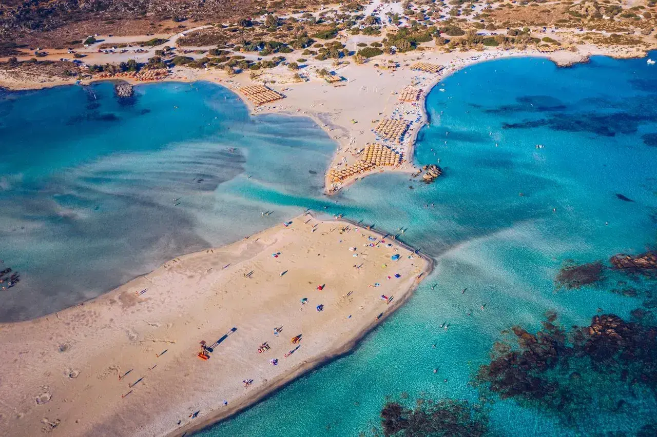 Rajska, piaszczysta kreta plaża Elafonisi z turkusową wodą i licznymi parasolami.