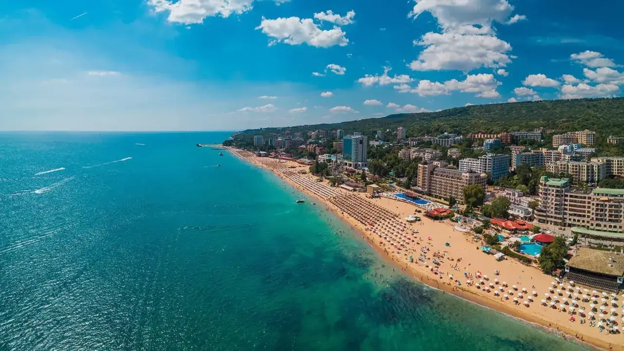 Słoneczna plaża z mnóstwem leżaków i turystów, turkusowe morze, hotele i zielone wzgórza. Warna, co zobaczyć!