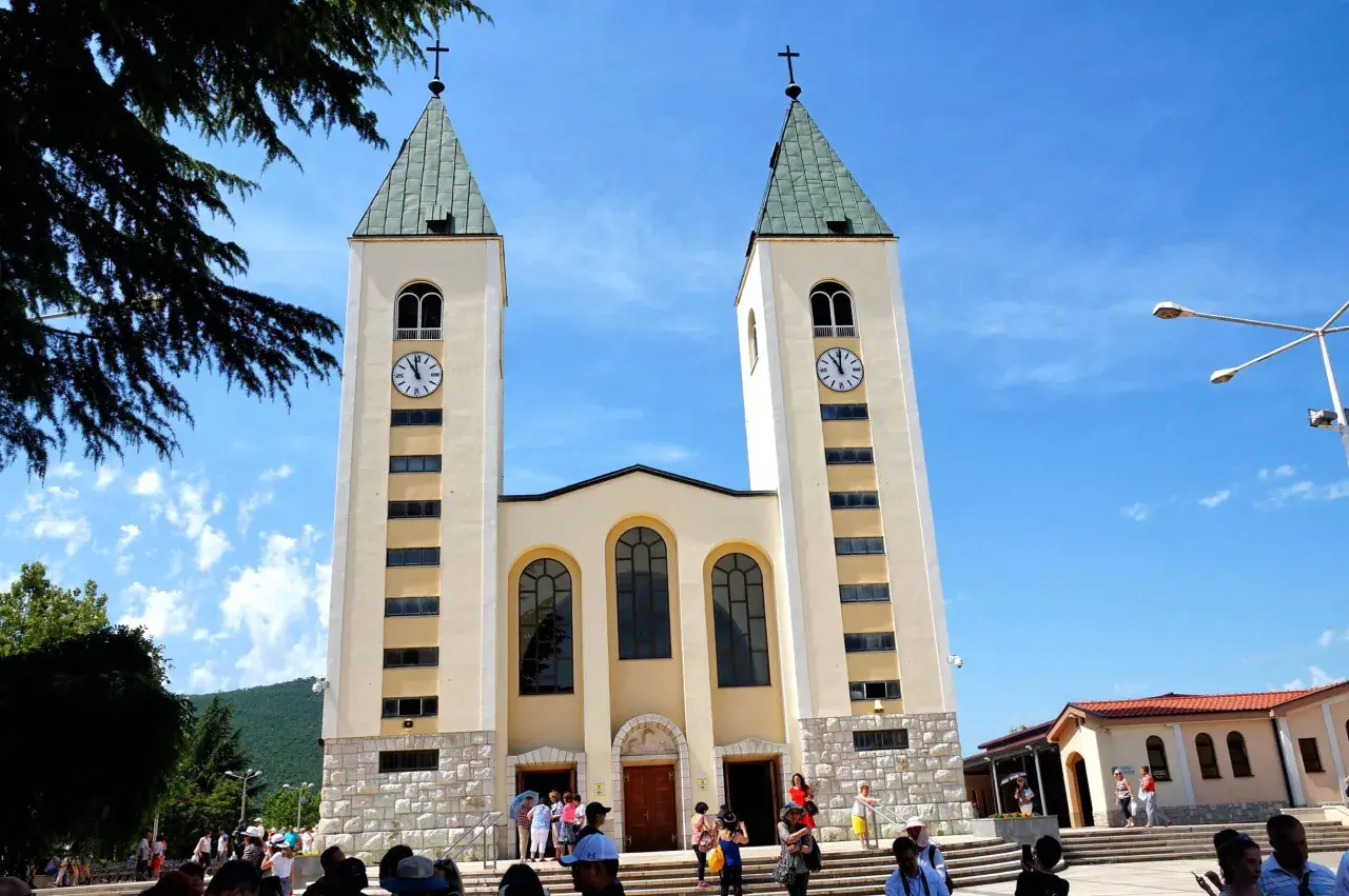 Kościół w Medziugorie, miejsce znane z objawień maryjnych. Tłumy pielgrzymów podziwiają architekturę.