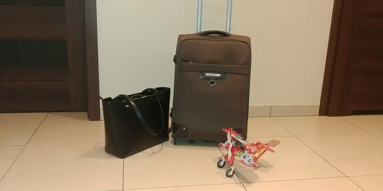Walizka, torebka i model samolotu czekają na lot samolotem w ciąży w 1 trymestrze.