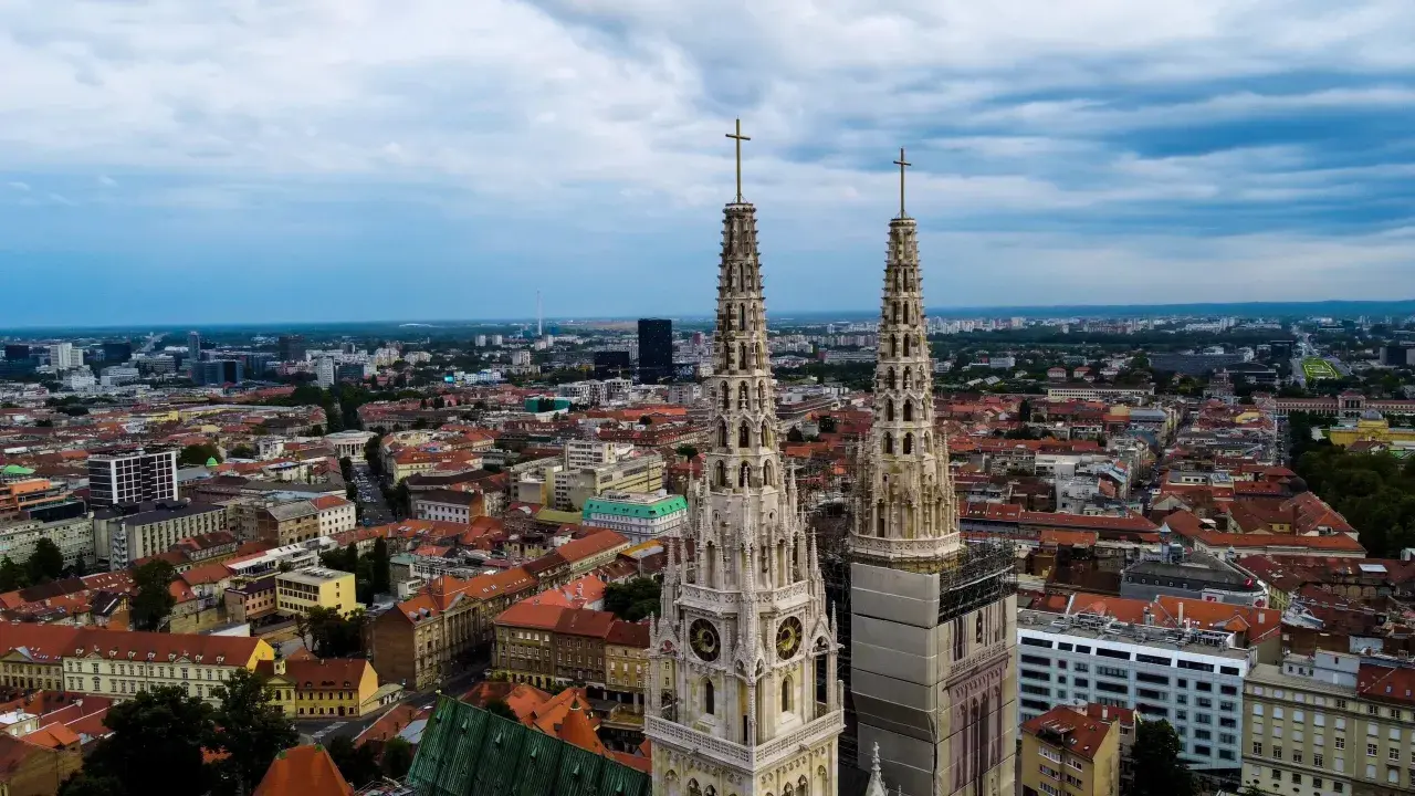 Dwie wieże katedry górują nad miastem. W oddali widać nowoczesne budynki i zielone tereny. To wspaniałe zagrzeb atrakcje.