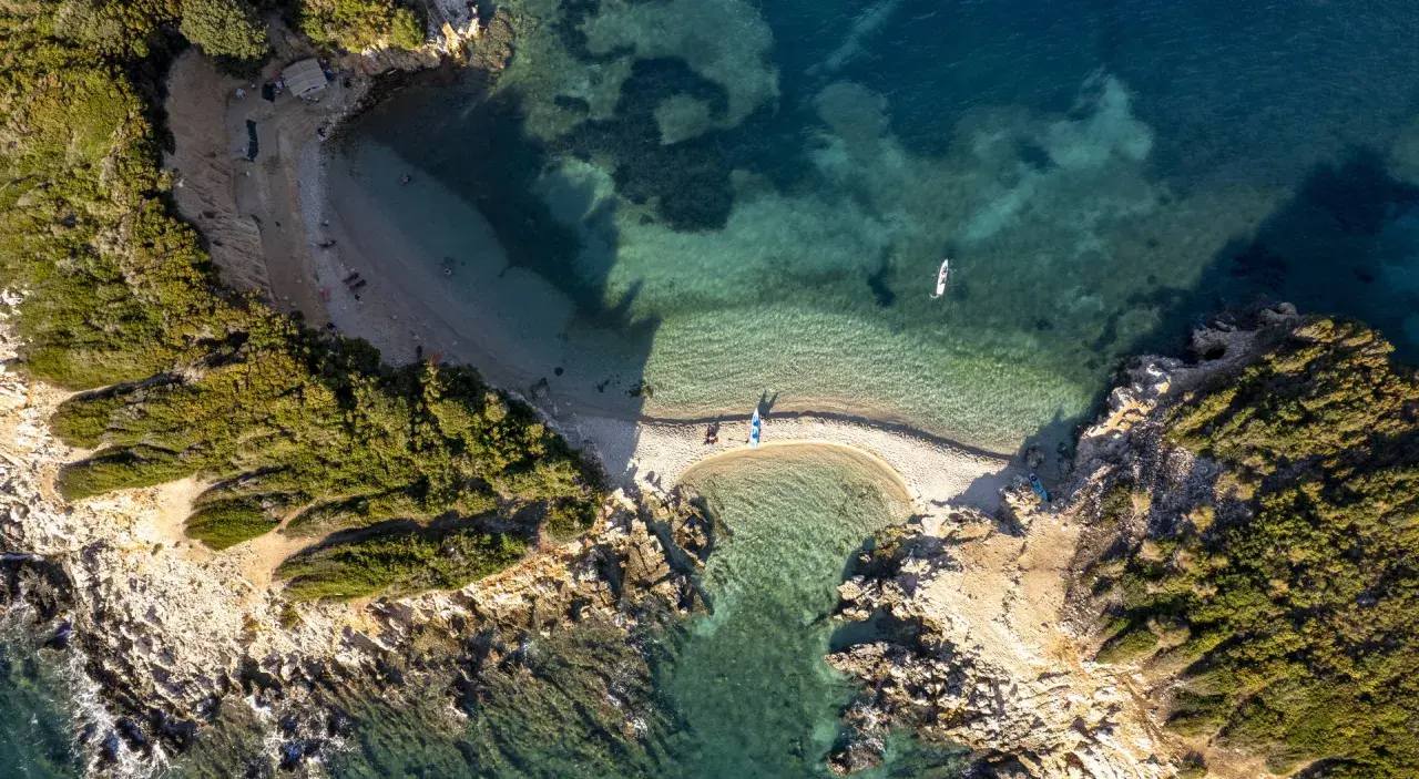 Albania, styczeń. Pogoda sprzyja wodnym aktywnościom na malowniczej plaży z turkusową wodą i kajakami.