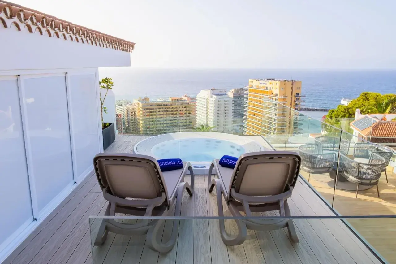 Relaks na tarasie z jacuzzi i widokiem na ocean w Fergus Puerto de la Cruz. Dwa leżaki czekają na gości.