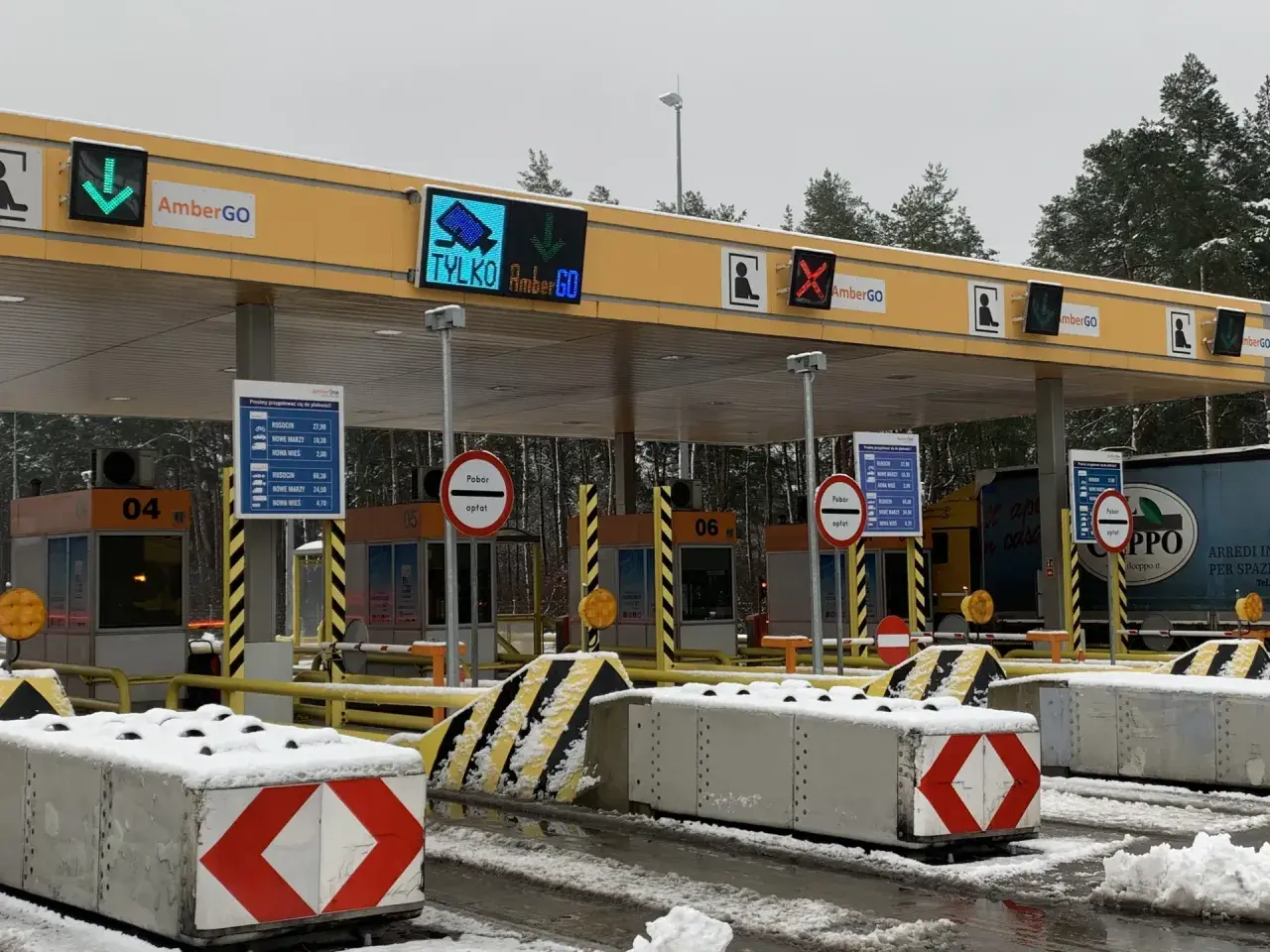 Oznaczenia na bramkach na autostradzie AmberGO: zielona strzałka w dół, czerwony krzyżyk, informacja o poborze opłat.