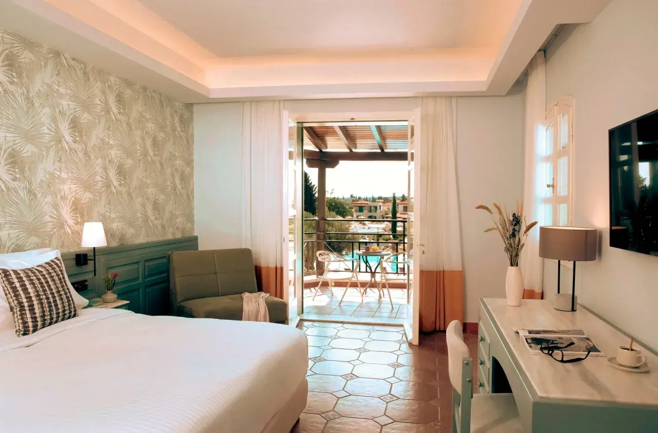 Pokój w Eretria Hotel & Spa Resort z widokiem na basen i morze. Wygodne łóżko, fotel i balkon zapraszają do relaksu.