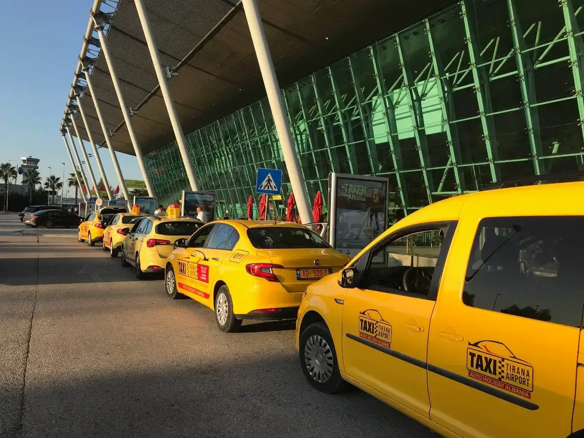Żółte taksówki czekają przed nowoczesnym terminalem lotniska. To dobry znak, jeśli zastanawiasz się, jak dolecieć do Albanii i dostać się do celu.