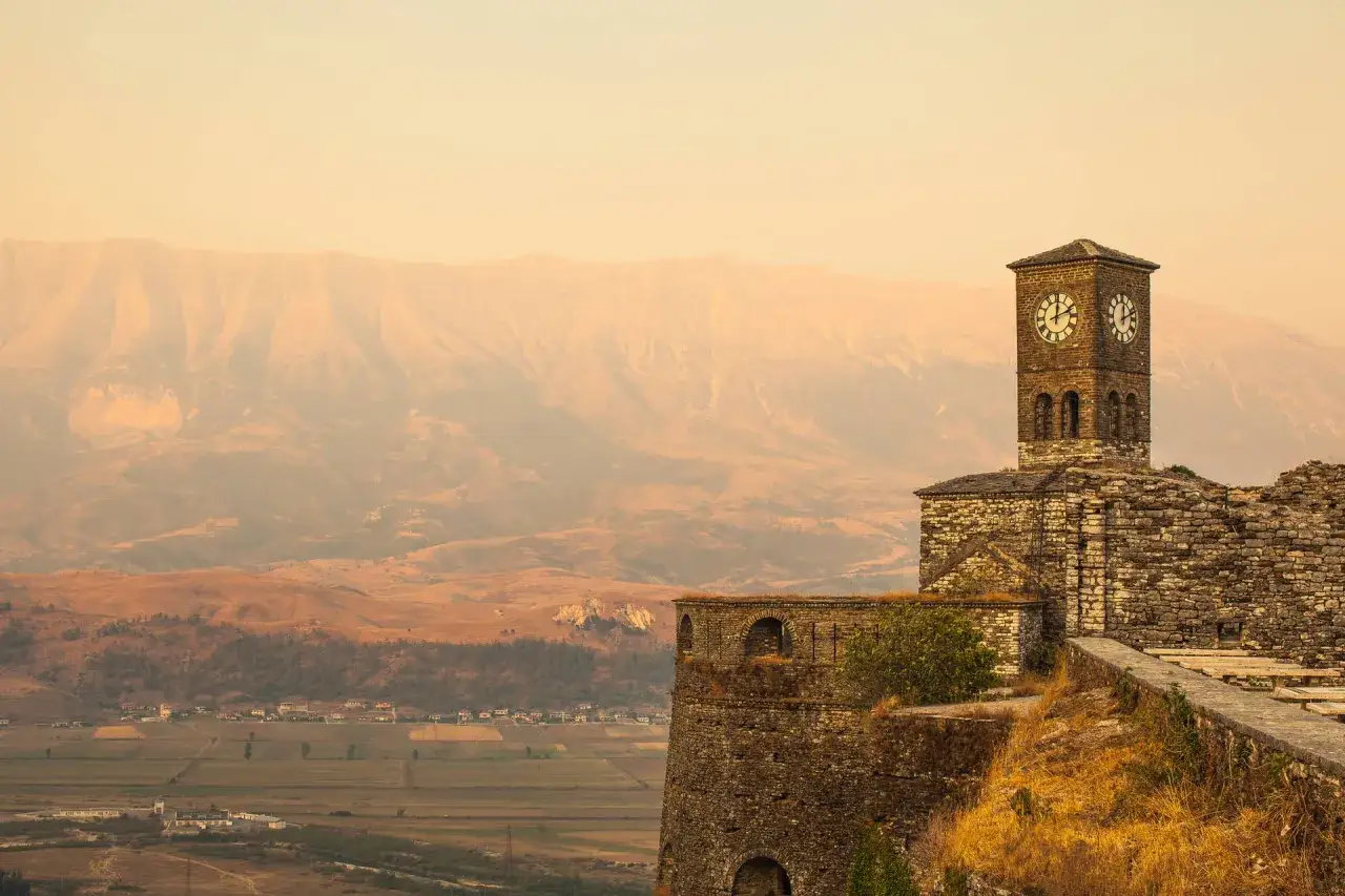 Albania, listopad. Pogoda łagodna, mglista, z widokiem na zabytkową wieżę zegarową i góry.