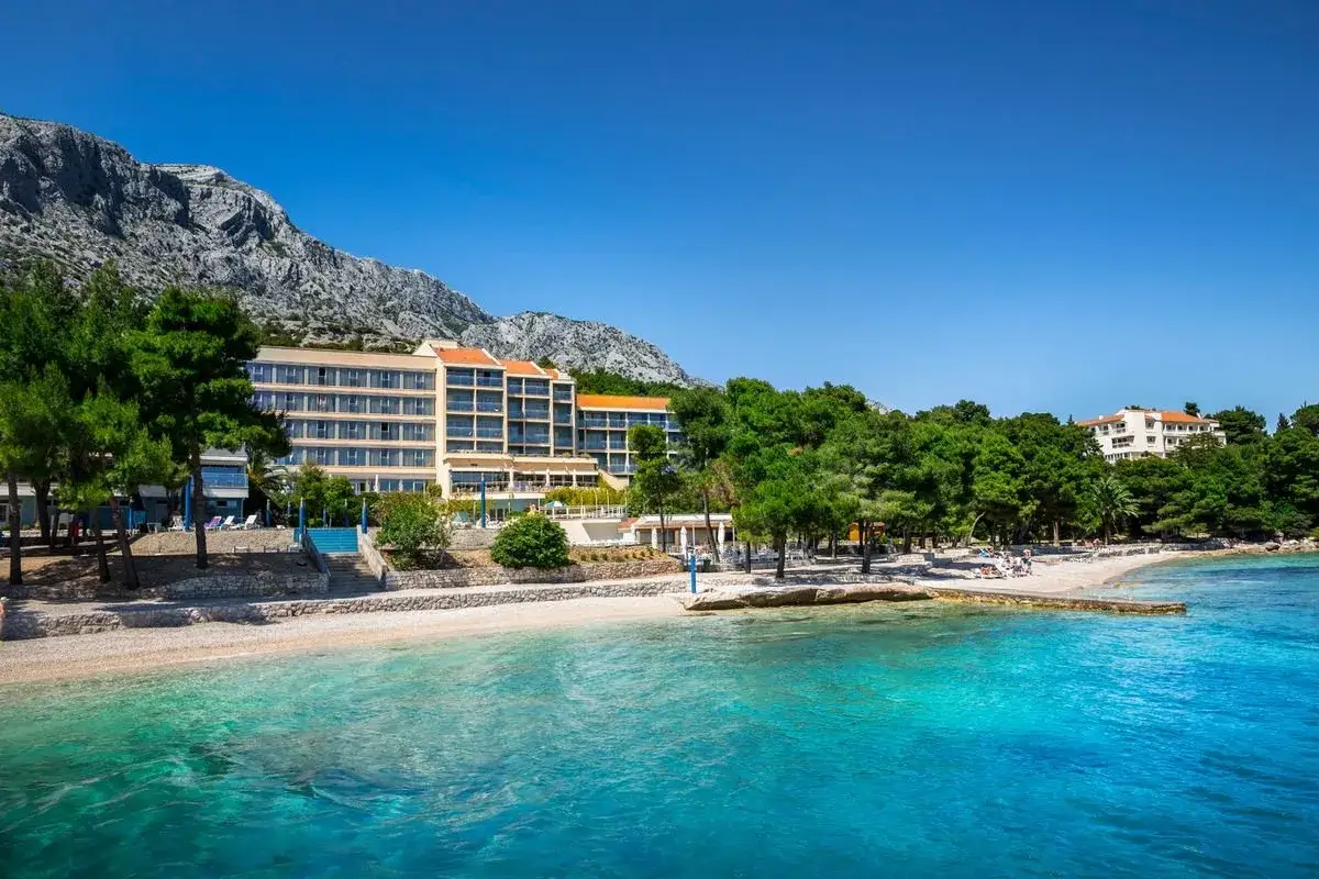Hotel przy plaży w Chorwacji z widokiem na góry i turkusowe morze.
