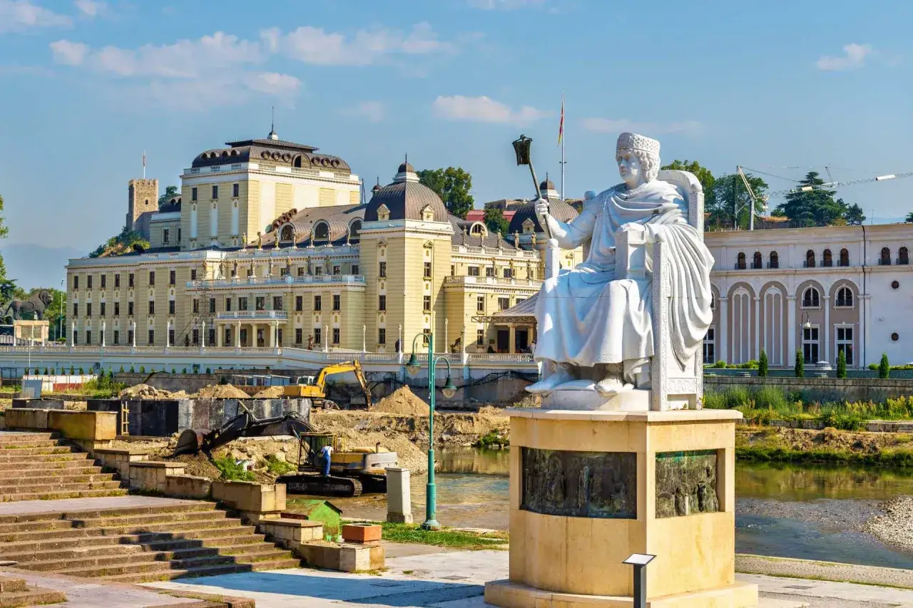 Pomnik wojownika na tle budynków i placu budowy w Skopje. Atrakcje miasta w słońcu.