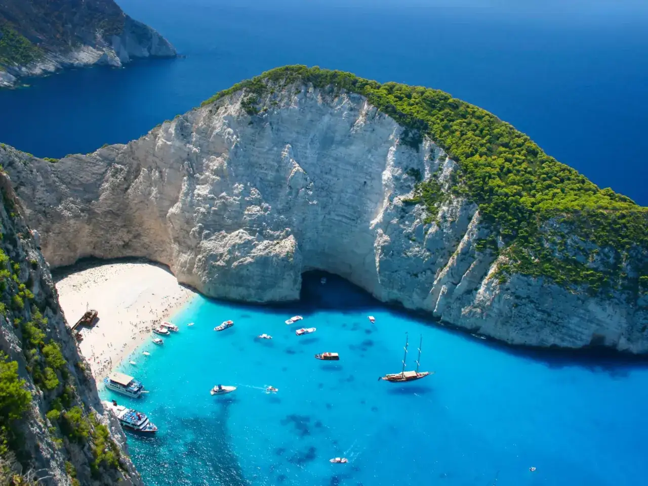 Navagio Beach, jedna z najpiękniejszych plaż w Grecji, z białym piaskiem, turkusową wodą i łodziami.