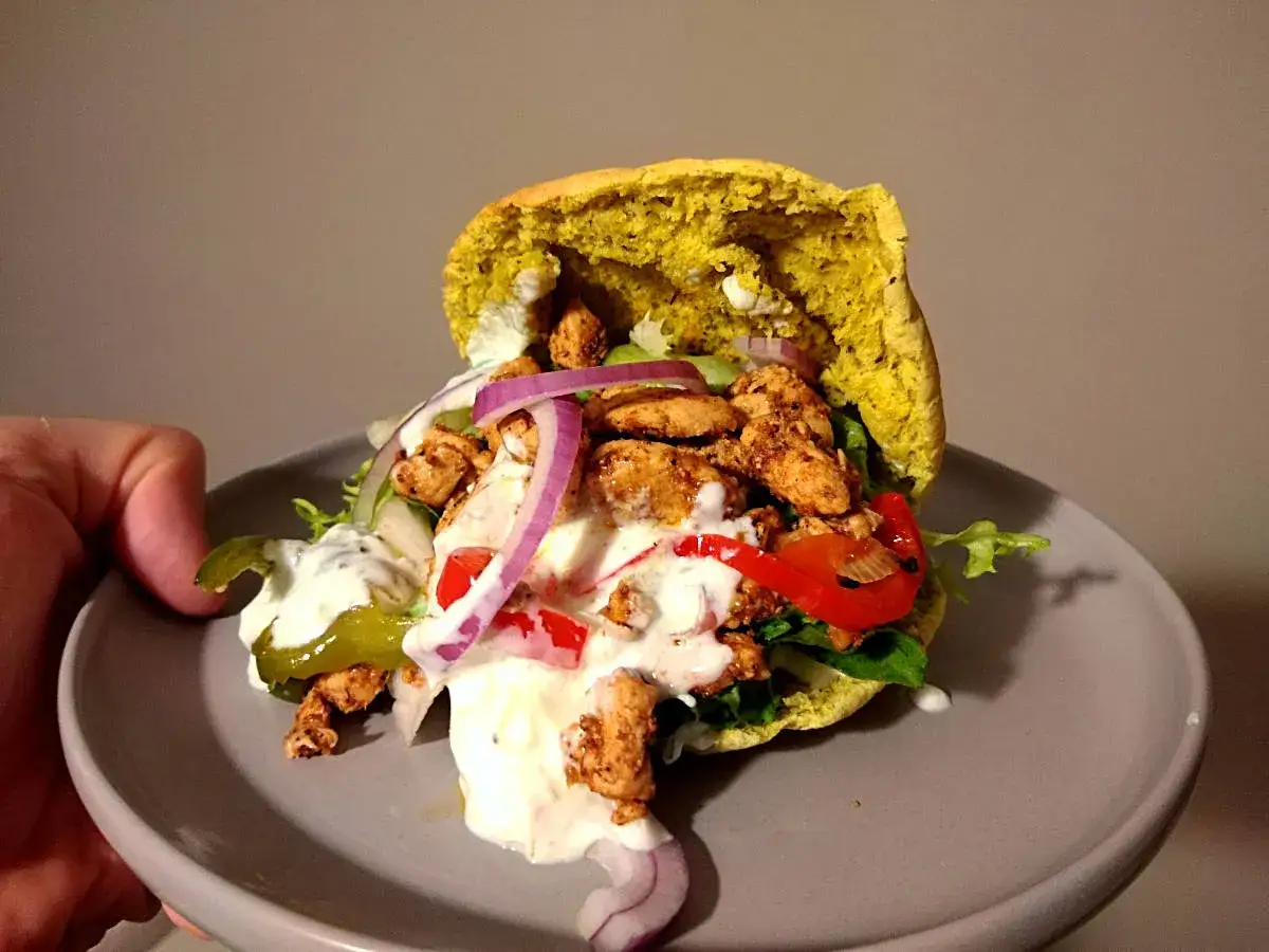 Pyszny gyros w picie z kurczakiem, warzywami i sosem. Idealny na szybki posiłek.