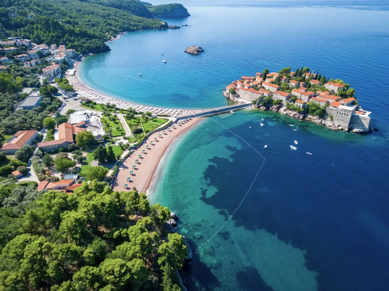 Malownicza wyspa Sveti Stefan połączona z lądem groblą, otoczona turkusowym morzem i piaszczystymi plażami. Czarnogóra plaże zachwycają!