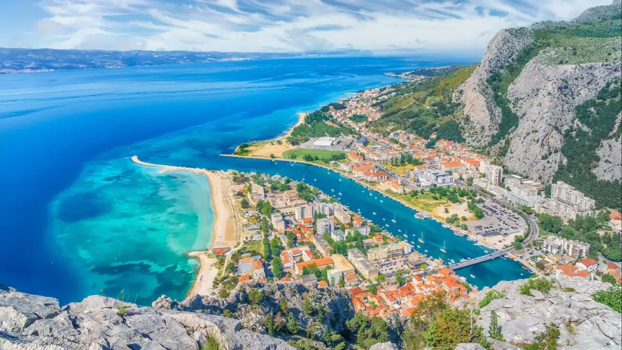 Widok na miasteczko nad turkusowym morzem, z górami w tle. To piękna riwiera Makarska, idealna na wakacje.