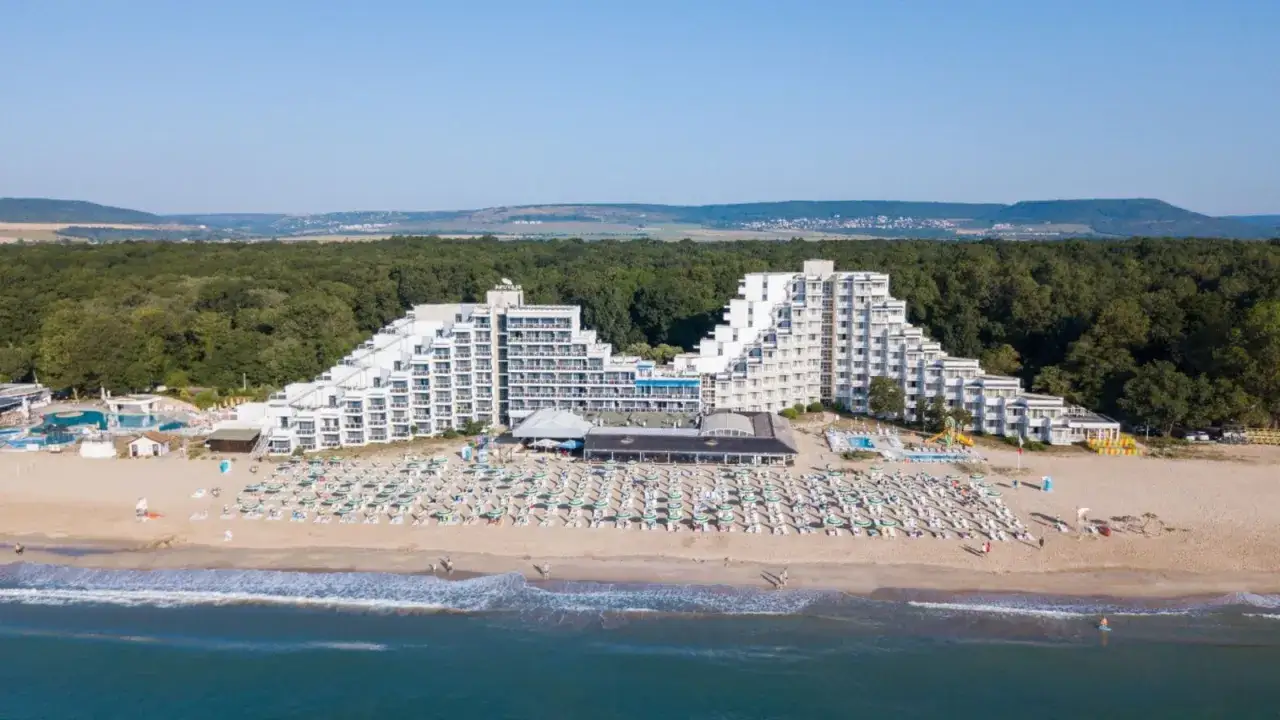 Słoneczna plaża w Albena Bułgaria z białymi hotelami o tarasowej architekturze, leżakami i basenami.