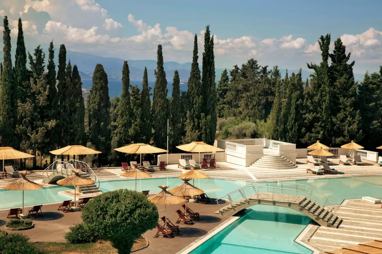 Relaks przy basenie w Eretria Hotel & Spa Resort, otoczonym cyprysami i z widokiem na morze.