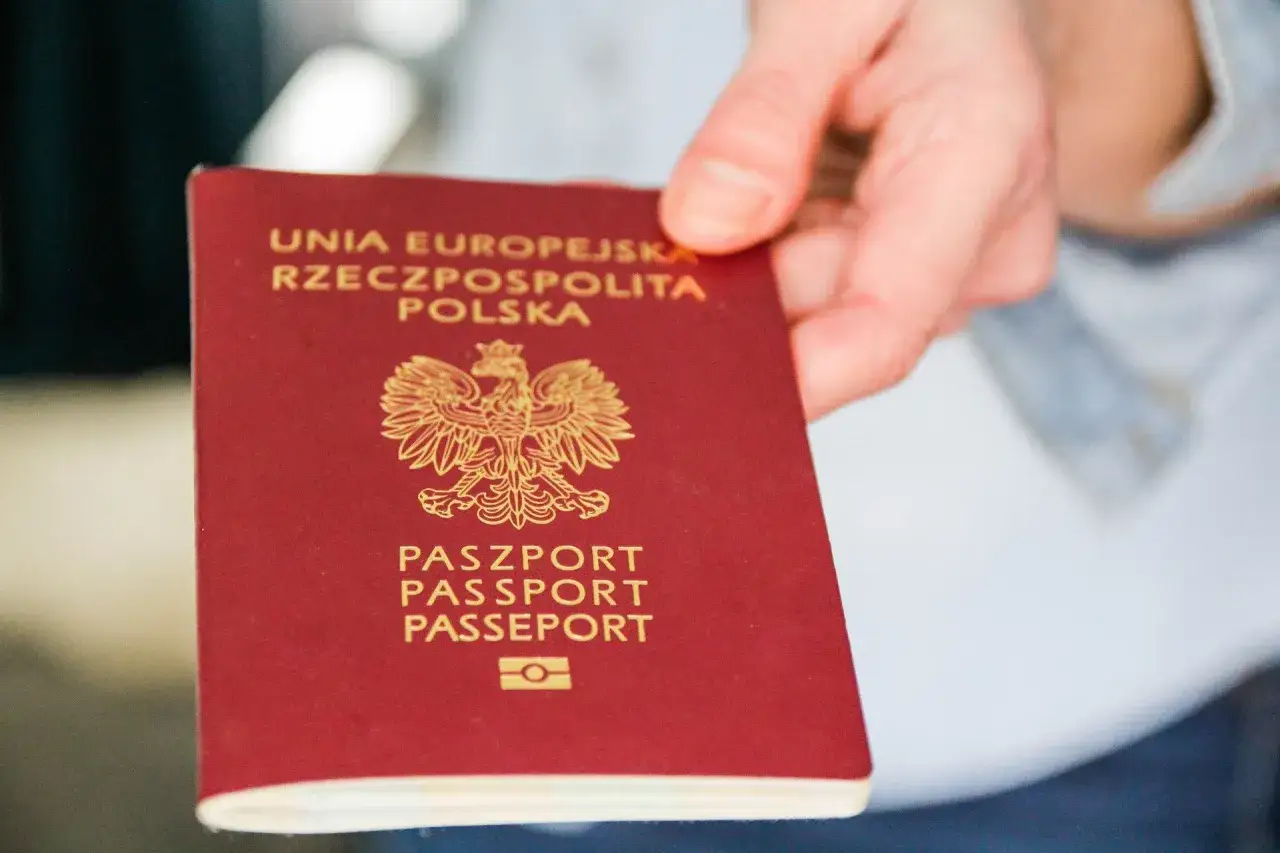 Dłoń trzyma polski paszport, gotowy do podróży samolotem. Czy wystarczy dowód osobisty?
