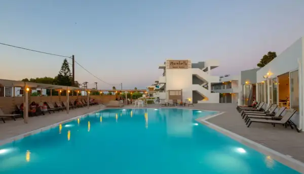 Basen i leżaki przy hotelu Marebello Beach Resort. Wieczorne światła odbijają się w wodzie.