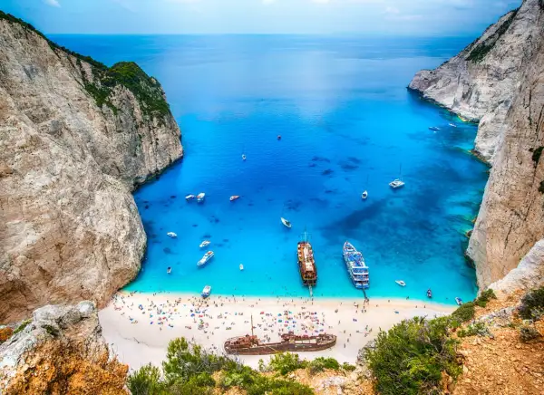 Zatoka Navagio, jedna z największych wysp greckich, z turkusową wodą, plażą pełną ludzi i wrakiem statku.