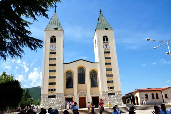 Kościół w Medziugorie, miejsce znane z objawień maryjnych. Tłumy pielgrzymów podziwiają architekturę.