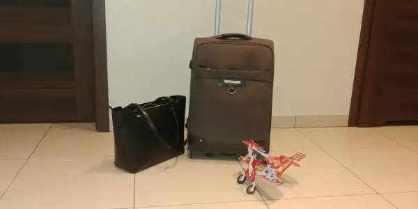 Walizka, torebka i model samolotu czekają na lot samolotem w ciąży w 1 trymestrze.