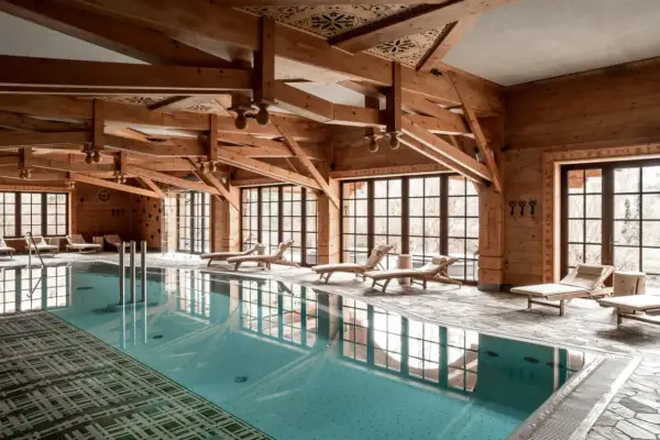 Drewniane belki, basen i leżaki tworzą atmosferę luksusowego spa.