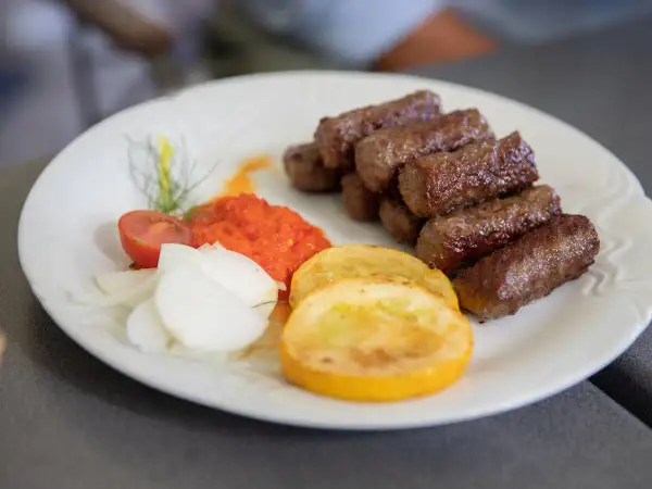Cevapi, klasyka kuchni słoweńskiej, podane z ajwarem, cebulą i pomidorem.
