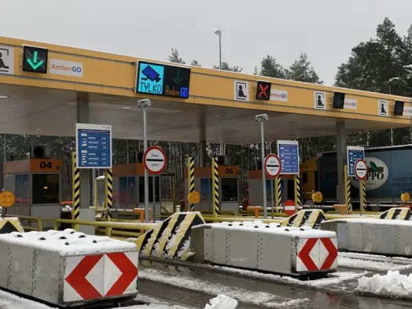 Oznaczenia na bramkach na autostradzie AmberGO: zielona strzałka w dół, czerwony krzyżyk, informacja o poborze opłat.