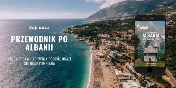 Piękna linia brzegowa Albanii, z widokiem na miasto i góry. Na ekranie telefonu przewodnik po Albanii, idealny na podróż.