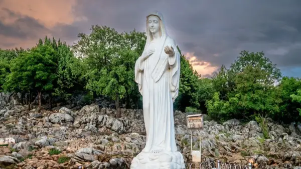 Biały posąg Matki Bożej na skalistym wzgórzu, miejsce pielgrzymek do Medjugorie.